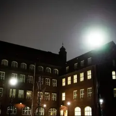 Mörkt tegelhus med många fönster lyser upp natten. Hvitfeldtska gymnasiet ser imponerande ut i det svaga ljuset.
