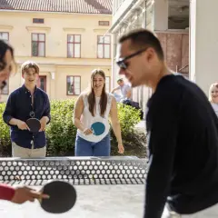 Elever spelar pingis utomhus vid Falu Frigymnasium. Soligt och glada miner bland ungdomarna.
