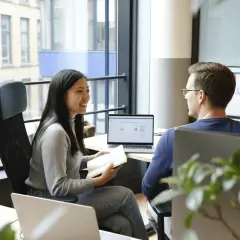 Två kollegor, en teknisk account manager och en kollega, diskuterar data på en stor skärm.