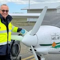 Man i gul jacka laddar elflygplan vid en green flight academy.