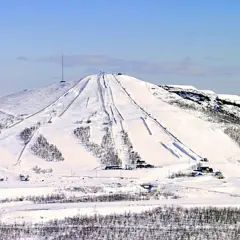 Snöklädda pister på ett berg med en mast på toppen, en vy som påminner om rymdgymnasiet Kiruna.