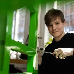 En ung man skruvar i ett dörrhandtag, en praktisk övning på Praktiska Gymnasiet Gamlestaden.
