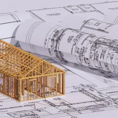 En trämodell av ett hus står på ritningar. En bra början för att förstå hur man blir arkitekt.