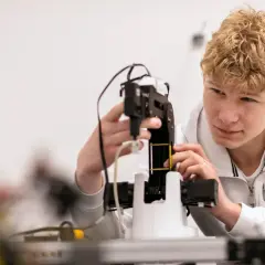 Ung man med blont lockigt hår arbetar med en robotarm vid nti Odenplan.