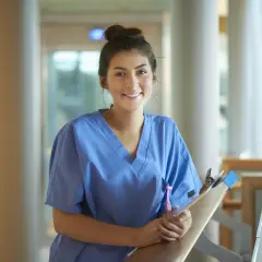 Glad ung kvinna i blå scrubs med en clipboard, redo för sin laborant utbildning.