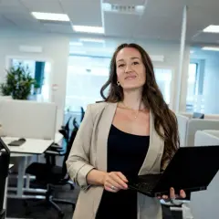 Kvinna med laptop i modernt kontorslandskap, redo att jobba med reklam.