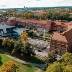 Luftfoto över Virginska gymnasiet med sina tegelbyggnader och en stor cykelparkering. Hösten färgar träden gyllene.
