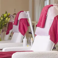 Välkomnande behandlingsstolar med röda och vita handdukar, redo för nästa kund. Perfekt för hudterapeut utbildning.
