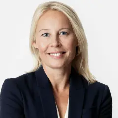 En kvinna med blont hår och blå ögon i mörk kavaj. Hon ler mot kameran, kanske efter att ha löst ett GDPR-incident.