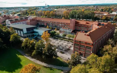 Luftfoto över Virginska gymnasiet med sina tegelbyggnader och en stor cykelparkering. Hösten färgar träden gyllene.