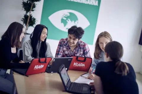 Elever på Klara Norra gymnasium samarbetar kring laptops.
