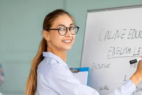 Glad lärare skriver "English Lesson" på en whiteboard. Perfekt för din engelska kurs distans.