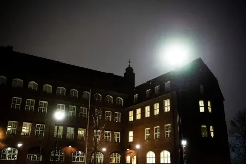 Mörkt tegelhus med många fönster lyser upp natten. Hvitfeldtska gymnasiet ser imponerande ut i det svaga ljuset.