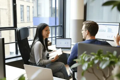 Två kollegor, en teknisk account manager och en kollega, diskuterar data på en stor skärm.