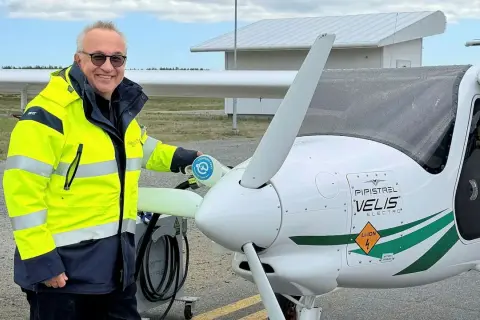 Man i gul jacka laddar elflygplan vid en green flight academy.