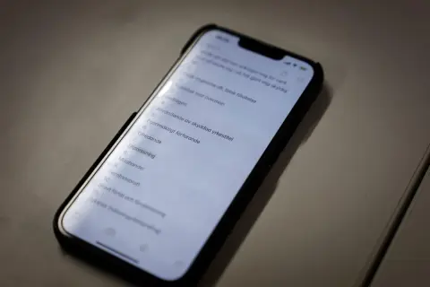 En mobiltelefon visar en lista med brott, inklusive "falsk tillvitelse". Listan kan vara en del av en juridisk process där skadestånd kan bli aktuellt.