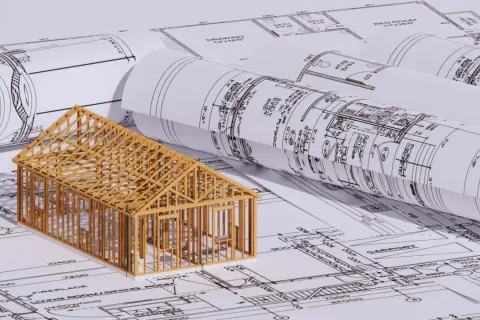 En trämodell av ett hus står på ritningar. En bra början för att förstå hur man blir arkitekt.