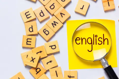 Förstoringsglas över ordet "english" på en gul post-it, omgivet av bokstavsbrickor. Perfekt för engelska 6 distans.