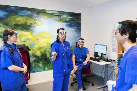 Personal med visir och blå kläder diskuterar gynekolog utbildning.