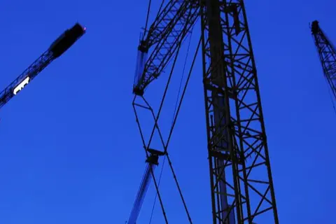 Byggkranar mot en mörkblå himmel. Ett ramavtal för framtida projekt.