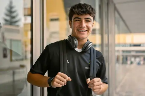 Ung kille med hörlurar och ryggsäck, redo för en **rig fotboll**-träning.