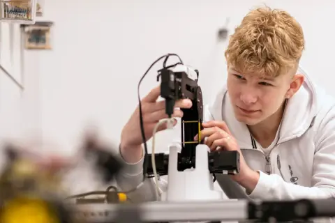 Ung man med blont lockigt hår arbetar med en robotarm vid nti Odenplan.