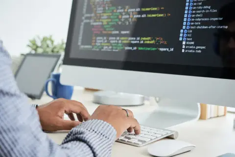 Person skriver kod på en datorskärm, en del av datorteknik 1a.