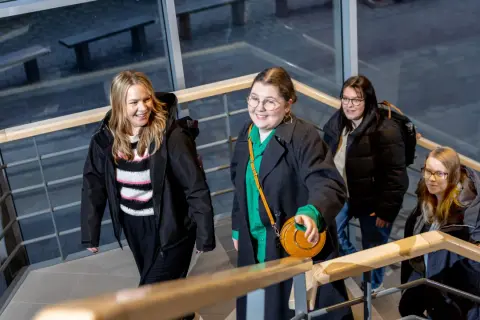 Fyra glada studenter går uppför trappan på campus Ljungby.