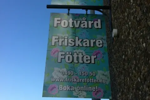 Skylt för "Fotvård Friskare Fötter" med blomstermönster. Erbjuder fotvård och fotvård utbildning. Boka online!