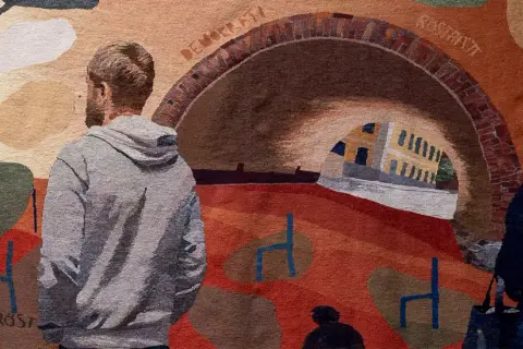 En vävd bild med människor och en valvbro. Kanske en scen från politices kandidatprogram Lund, med symboler för frihet och röster.
