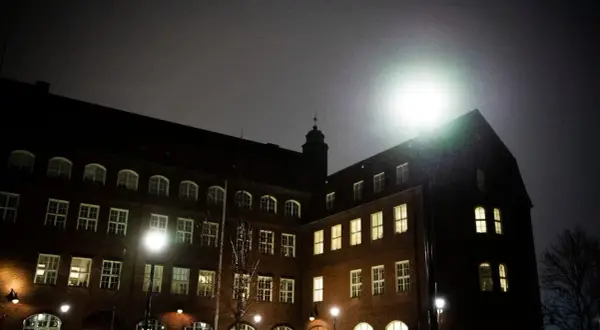 Mörkt tegelhus med många fönster lyser upp natten. Hvitfeldtska gymnasiet ser imponerande ut i det svaga ljuset.