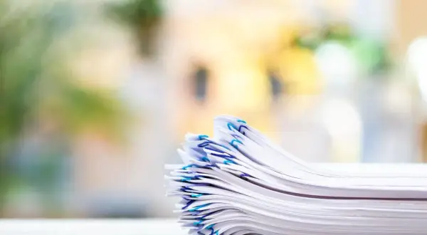 En hög med papper, organiserad med blå gem, som representerar vikten av att följa artikel 30 GDPR för dataskydd.