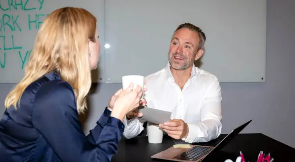 En management konsult diskuterar med en kollega över en kaffekopp.