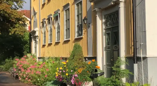 En gul träbyggnad med blommor framför, en del av stora segerstad naturbrukscentrum.