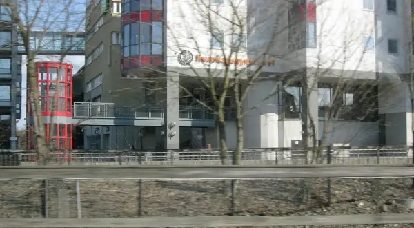Modern byggnader med glasfasader och en röd, cylindrisk hiss. Skylten "Kunskapsgymnasiet Globen" syns på en av byggnaderna.