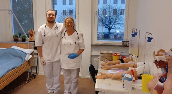 Två glada medarbetare från Medlearn AB i en övningssal med medicinsk utrustning.
