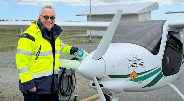 Man i gul jacka laddar elflygplan vid en green flight academy.