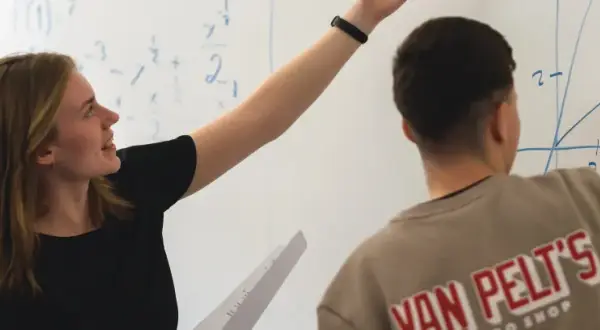 En elev på Realgymnasiet Uppsala pekar på en matematisk formel på tavlan.