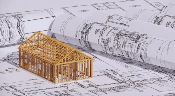 En trämodell av ett hus står på ritningar. En bra början för att förstå hur man blir arkitekt.