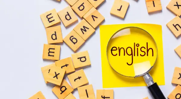 Förstoringsglas över ordet "english" på en gul post-it, omgivet av bokstavsbrickor. Perfekt för engelska 6 distans.