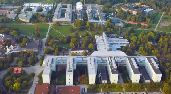 Stora universitetsbyggnader med gröna ytor och träd. En modern campusmiljö som visar en framgångsrik integration av ekonomi och IT.