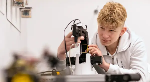 Ung man med blont lockigt hår arbetar med en robotarm vid nti Odenplan.