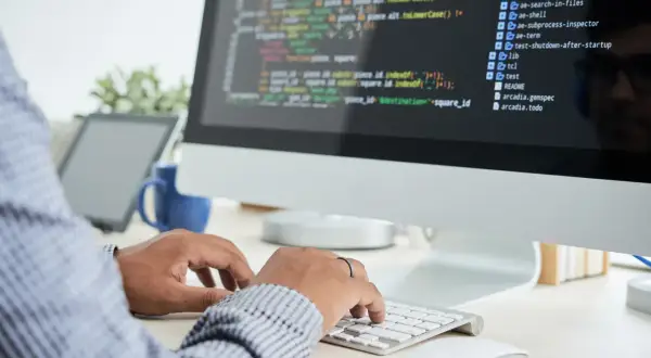 Person skriver kod på en datorskärm, en del av datorteknik 1a.