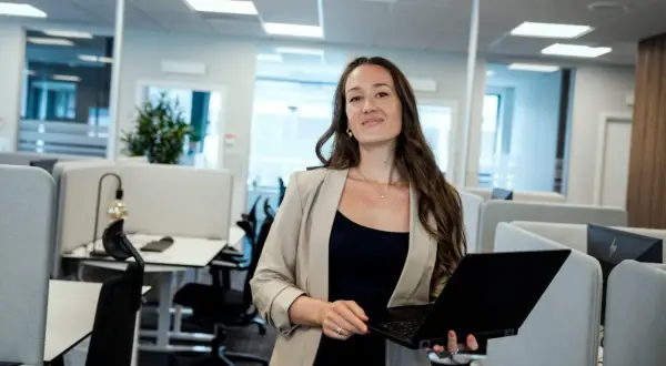 Kvinna med laptop i modernt kontorslandskap, redo att jobba med reklam.