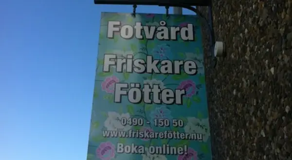 Skylt för "Fotvård Friskare Fötter" med blomstermönster. Erbjuder fotvård och fotvård utbildning. Boka online!