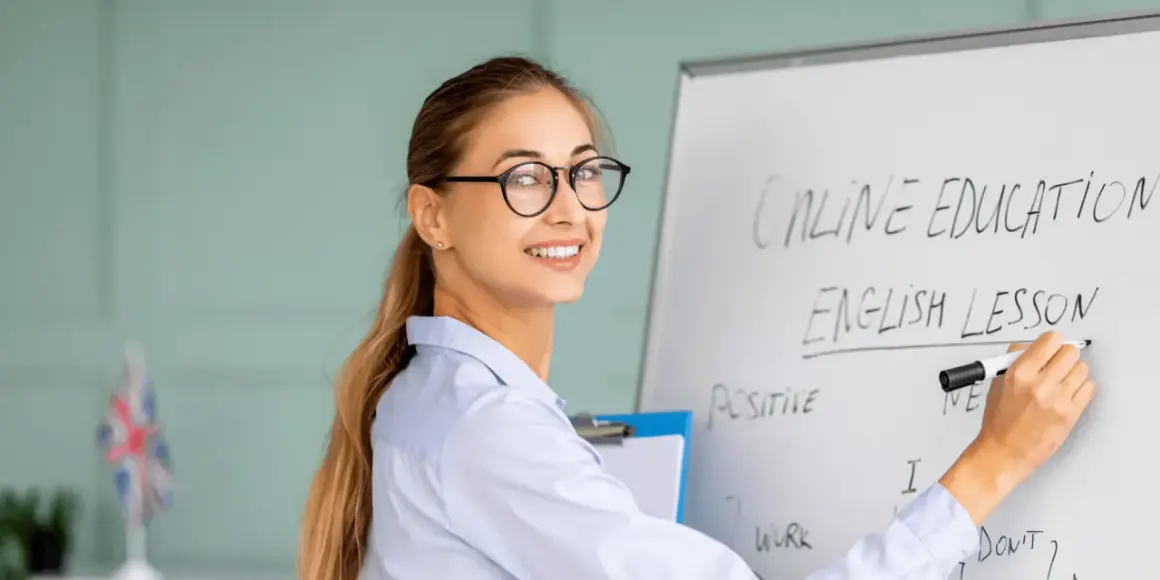 Glad lärare skriver "English Lesson" på en whiteboard. Perfekt för din engelska kurs distans.