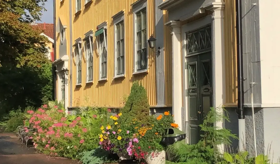 En gul träbyggnad med blommor framför, en del av stora segerstad naturbrukscentrum.