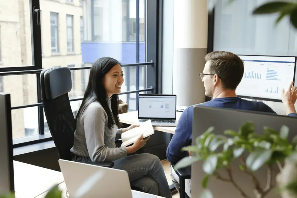 Två kollegor, en teknisk account manager och en kollega, diskuterar data på en stor skärm.