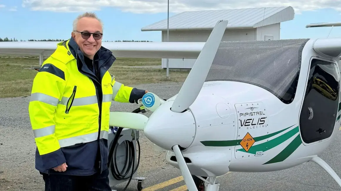 Man i gul jacka laddar elflygplan vid en green flight academy.