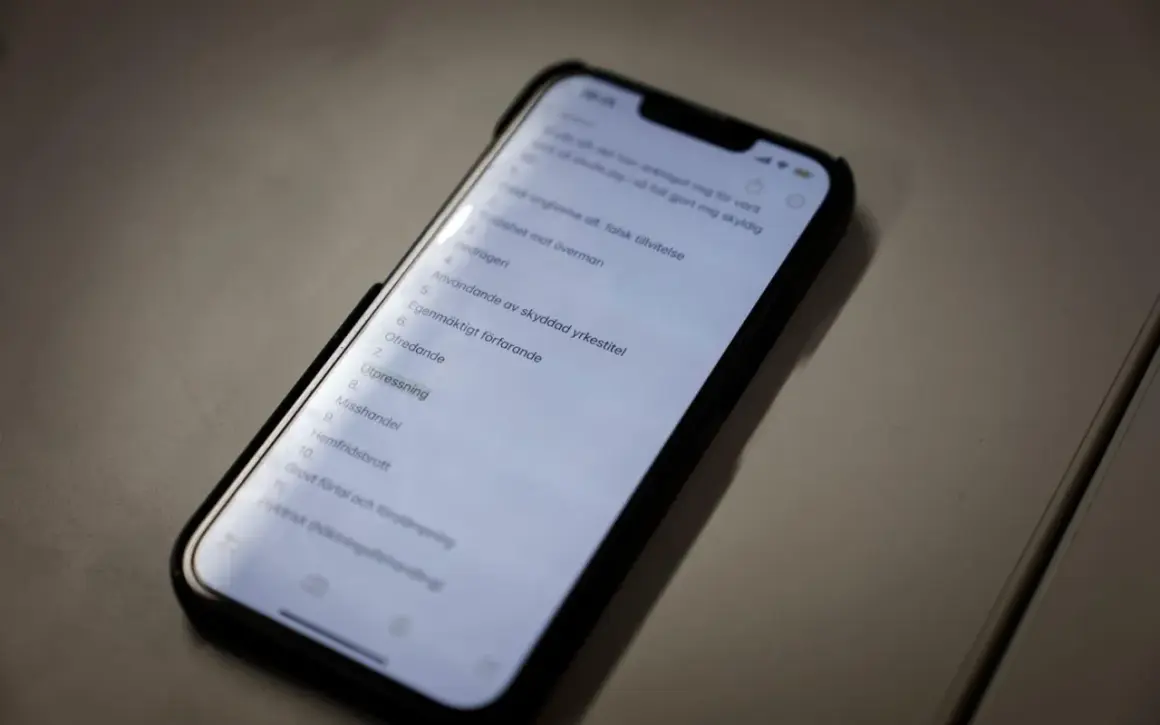 En mobiltelefon visar en lista med brott, inklusive "falsk tillvitelse". Listan kan vara en del av en juridisk process där skadestånd kan bli aktuellt.